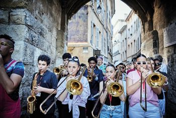 Photo de jeunes musiciens jouant des cuivres dans la rue en marchant