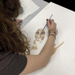 photo d'une personne en train de peindre sur une feuille un visage